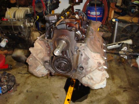 1989 Ford Bronco - Engine block with timing chain and gears visible, resting on an engine stand with oil pan below.