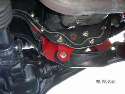 1996 Ford Bronco - A close-up view of a red suspension component attached to the undercarriage of a vehicle.