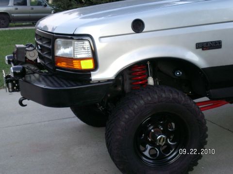 1996 Ford Bronco - A silver 1996 Ford Bronco is shown with modifications including an aftermarket bumper and red suspension components.