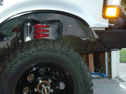 1996 Ford Bronco - This photo shows the suspension components of a truck, including a red coil spring and shock absorber.