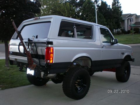 1996 Ford Bronco - This lifted 1996 Ford Bronco features a two-tone paint scheme and a rifle mounted on its rear carrier.