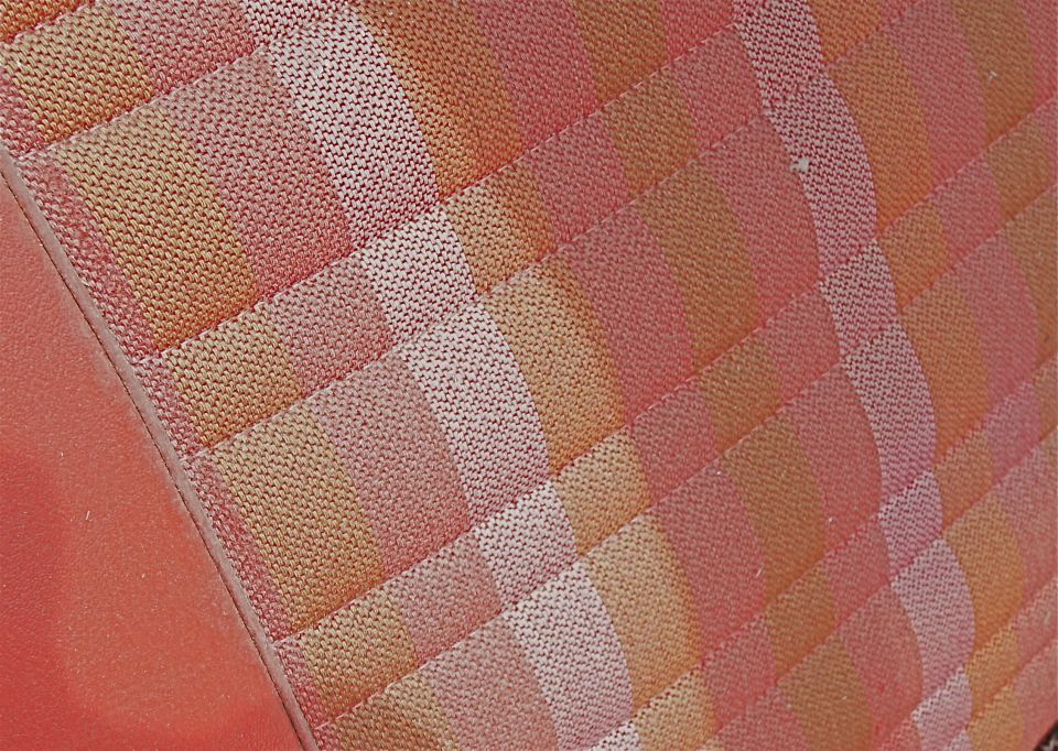 Close-up of patterned car seat fabric in shades of orange and pink