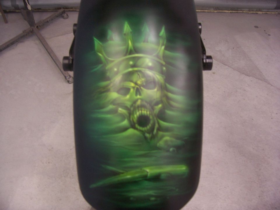 Motorcycle fender with airbrushed green skull wearing a crown and holding a knife