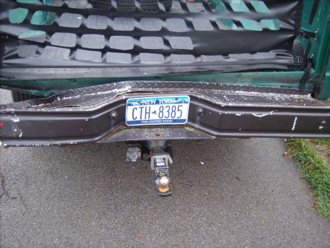 1979 Ford F-250 - The rear bumper of a green truck displays a New York license plate and a trailer hitch assembly.