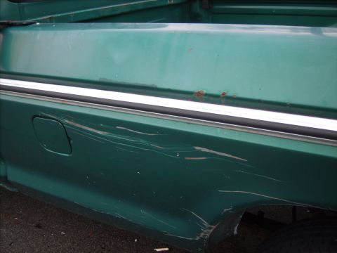 1979 Ford F-250 - Side view of a green 1979 Ford F-250 pickup truck bed with visible damage and trim.