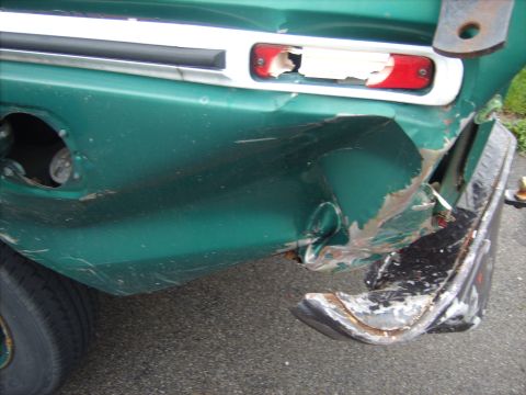 1979 Ford F-250 - The rear of a green truck shows extensive damage to the body and a broken taillight assembly.