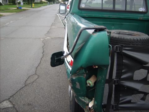 1979 Ford F-250 - A green 1979 Ford F-250 pickup truck is shown from the rear, with visible damage to the passenger side quarter panel.