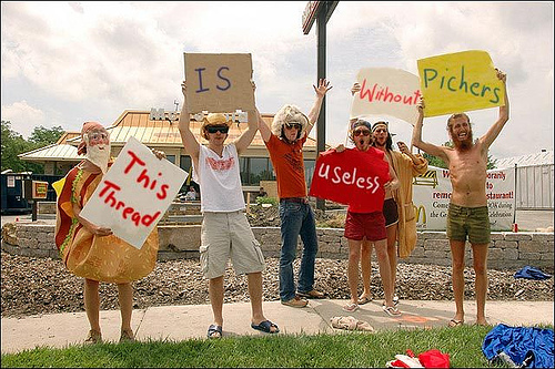 People holding signs that say 'This Thread IS Useless Without Pichers'