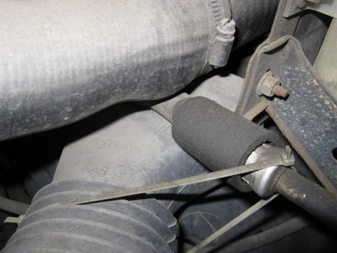 1990 Ford Bronco - Close-up view of engine bay components, including hoses and a metal bracket.