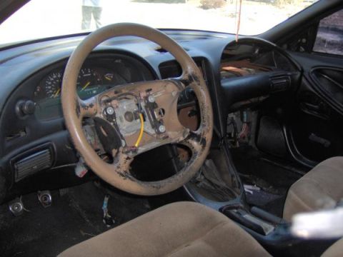 1994 Ford Mustang - The interior of a car shows a disassembled dashboard and steering wheel, with exposed wiring.