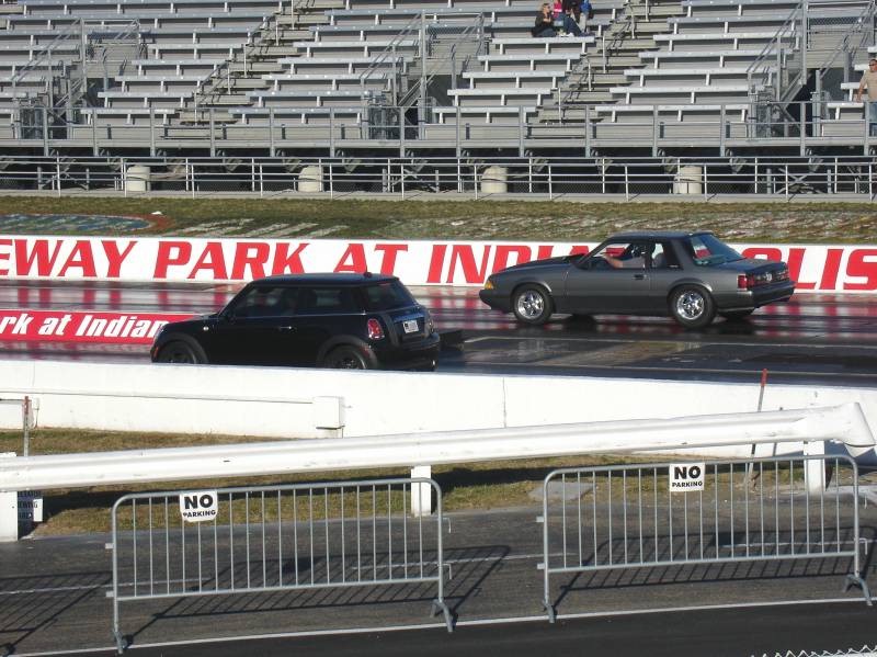 Black MINI Cooper beside gray Mustang on drag strip at Indianapolis