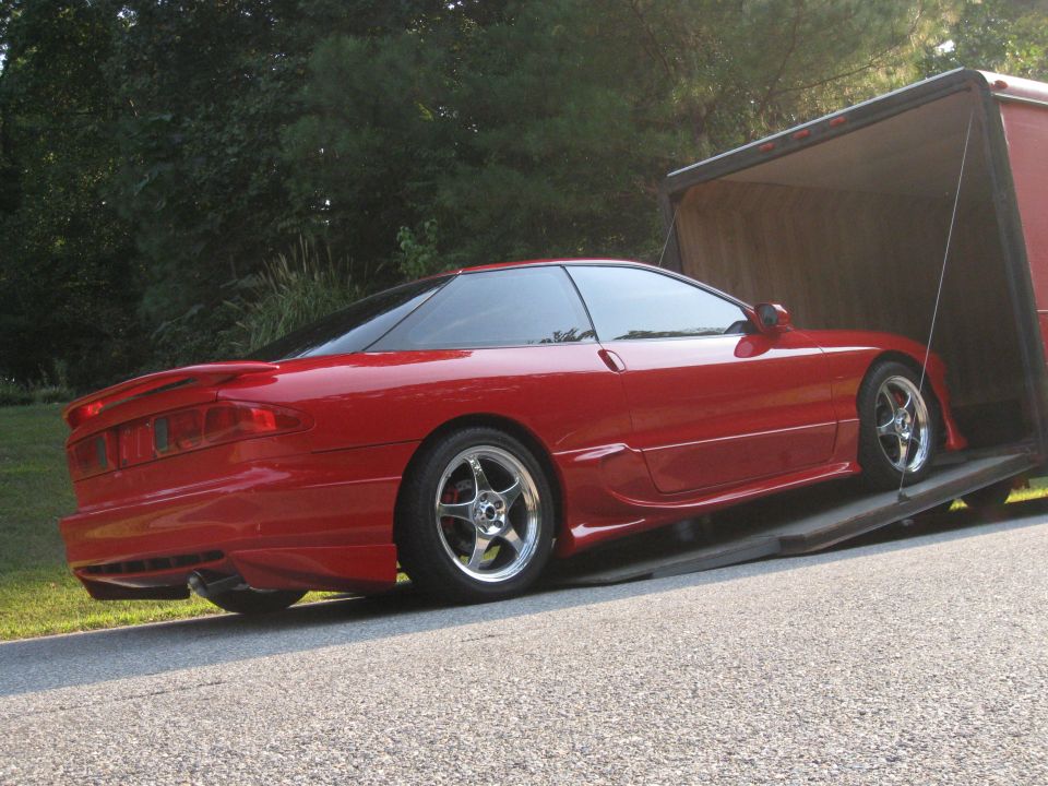 Red 1994 Ford Probe coupe with aftermarket wheels being loaded onto a trailer