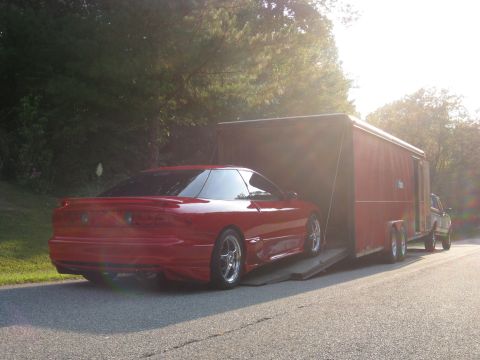 1994 Ford Probe - A red 1994 Ford Probe is being loaded into a red trailer by a truck.