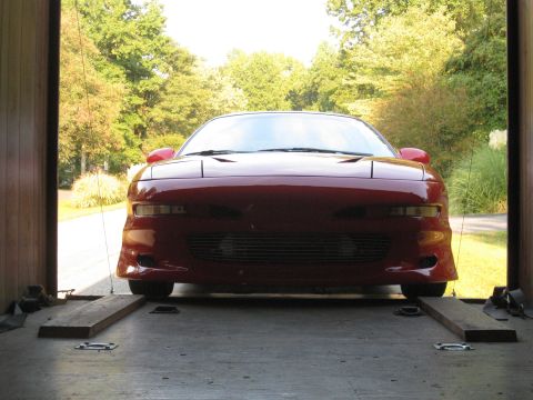 1994 Ford Probe - A red sports car is positioned on wooden ramps inside a trailer, ready for transport.