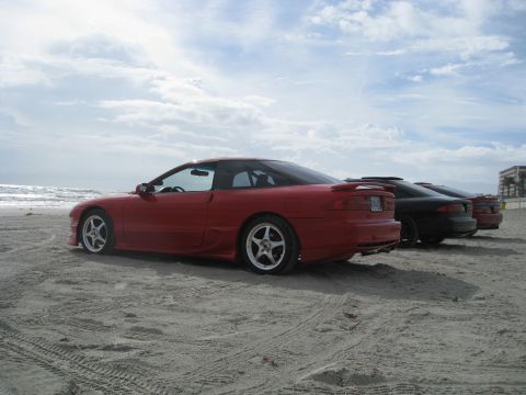 1994 Ford Probe - Three coupes are parked on a beach with the ocean in the background.