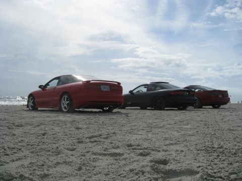 1994 Ford Probe - Three Ford Probes parked on a sandy beach with the ocean in the background.