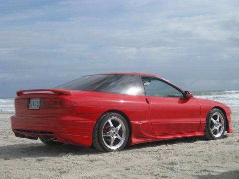 1994 Ford Probe - This red 1994 Ford Probe is parked on a sandy beach with the ocean in the background.