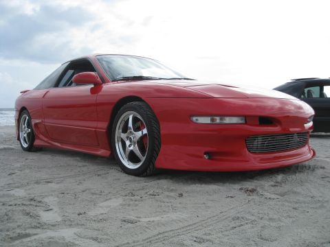 1994 Ford Probe - A red 1994 Ford Probe is parked on a sandy beach with the ocean in the background.
