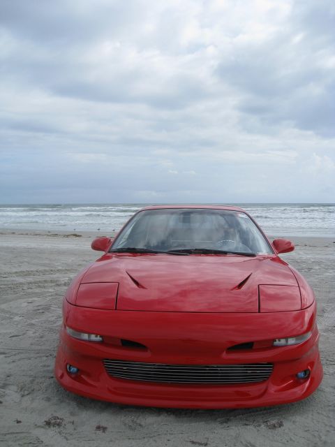1994 Ford Probe - Front view of a red sports car with pop-up headlights on a beach.