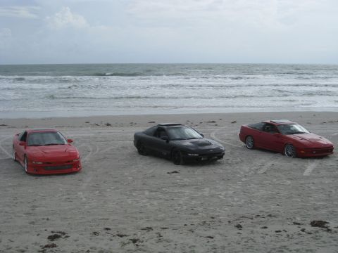 1994 Ford Probe - Three 1994 Ford Probes are lined up on the sand with the ocean waves in the background.
