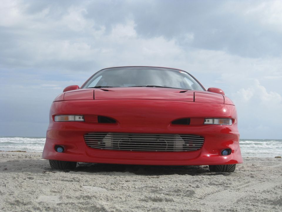 1994 Ford Probe front view on a sandy beach with ocean in background