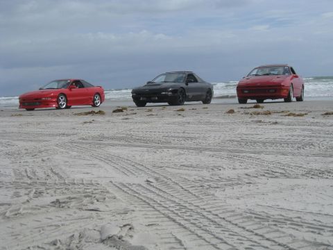 1994 Ford Probe - Three 1994 Ford Probes parked on a sandy beach with the ocean in the background.
