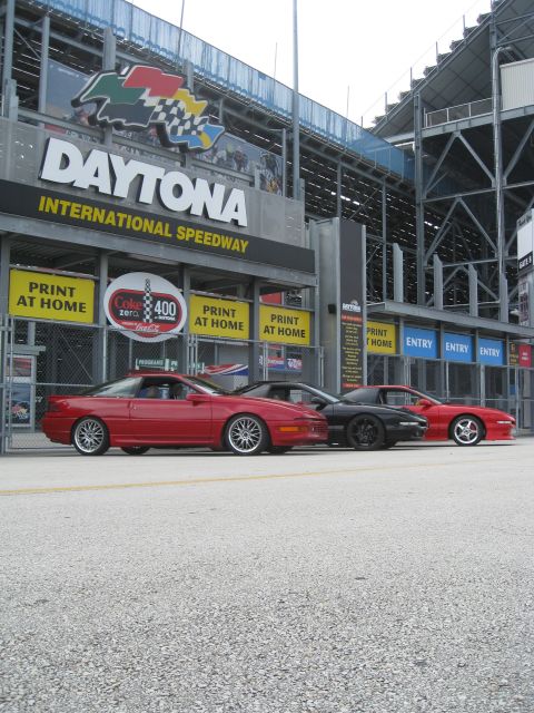 1994 Ford Probe - Three cars are parked in front of the Daytona International Speedway entrance.