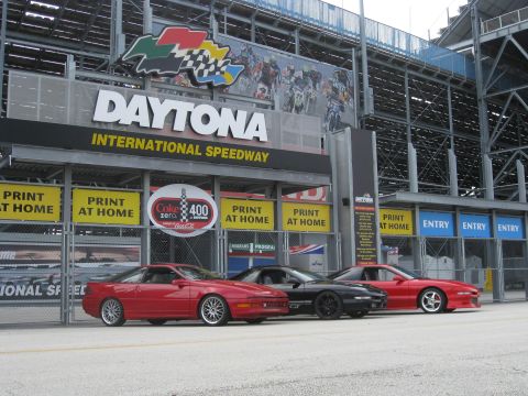 1994 Ford Probe - Three Ford Probes are lined up outside Daytona International Speedway, with the iconic entrance signage overhead.