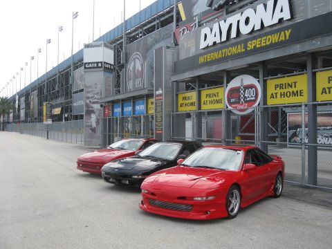 1994 Ford Probe - Three Ford Probe cars are parked in front of the Daytona International Speedway entrance.