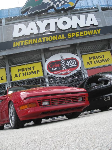 1994 Ford Probe - Two sports cars are parked in front of the Daytona International Speedway grandstands.