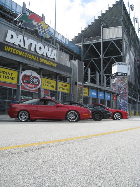 1994 Ford Probe - Three cars are parked in front of the Daytona International Speedway grandstands.