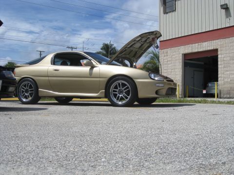 1994 Ford Probe - Gold 1994 Ford Probe coupe parked outside a building with its hood open.
