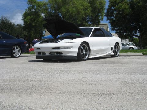1994 Ford Probe - A white 1994 Ford Probe is parked with its hood up, alongside another vehicle.