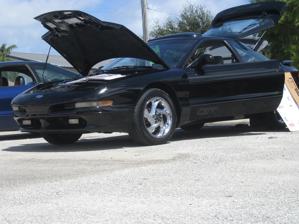 Black 1994 Ford Probe GT with hood and rear hatch open, chrome wheels, parked on asphalt