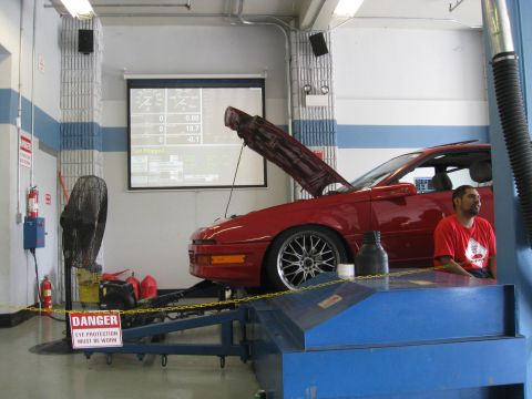 1994 Ford Probe - A red 1994 Ford Probe is positioned on a dynamometer for testing, with its hood open.