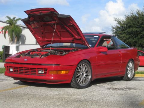 1994 Ford Probe - A red 1994 Ford Probe is parked with its hood open, revealing the engine bay.