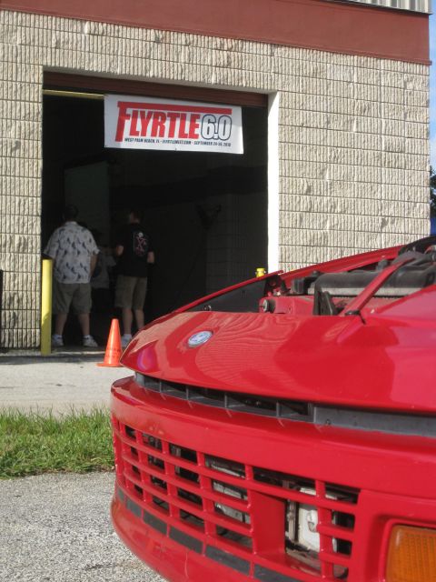 1994 Ford Probe - Front view of a red car with its hood up, parked outside a building with a banner.