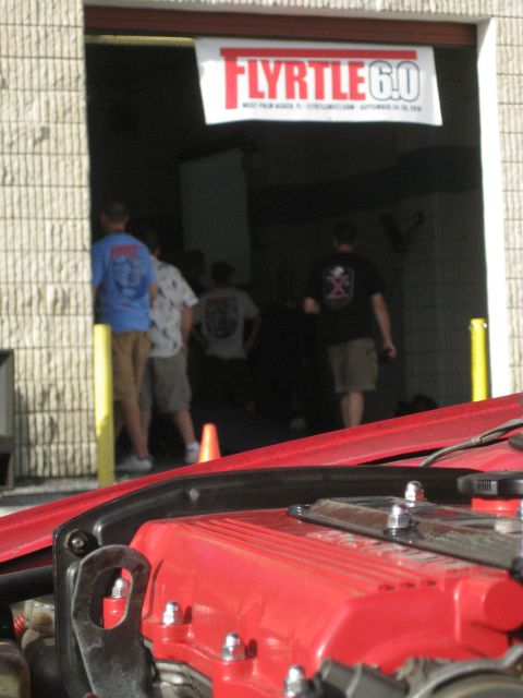 1994 Ford Probe - A red engine bay is visible in the foreground, with a banner for "FLYRTLE 6.0" hanging above an open garage door.