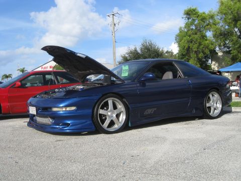 1994 Ford Probe - A blue 1994 Ford Probe GT is displayed with its hood up, parked next to another vehicle.