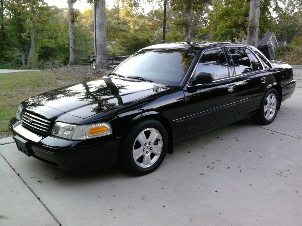 Black Ford Crown Victoria sedan, front 3/4 view on driveway