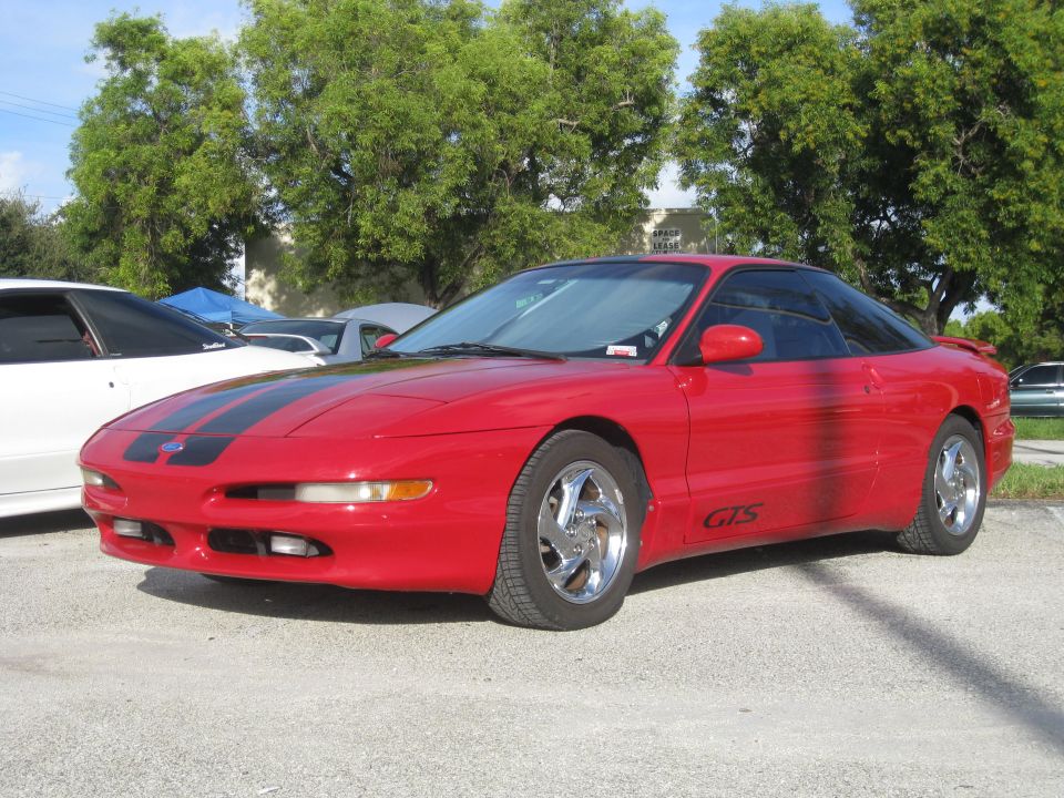 Red 1994 Ford Probe with black racing stripes on hood and roof. GTS badge on side