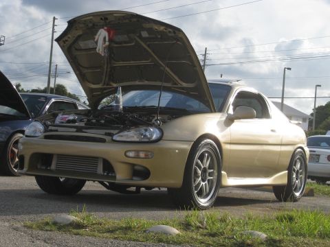 1994 Ford Probe - A gold 1994 Ford Probe is parked with its hood open, revealing the engine bay and aftermarket wheels.