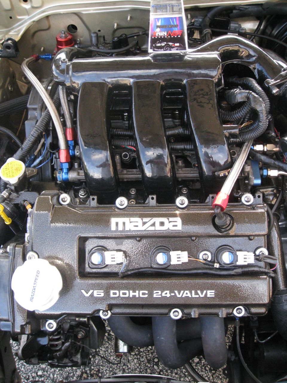 Close-up of a Mazda V6 DOHC 24-valve engine with custom intake manifold and braided fuel lines