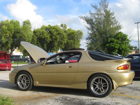 1994 Ford Probe - A gold coupe with its hood open is parked outdoors, with other vehicles visible in the background.