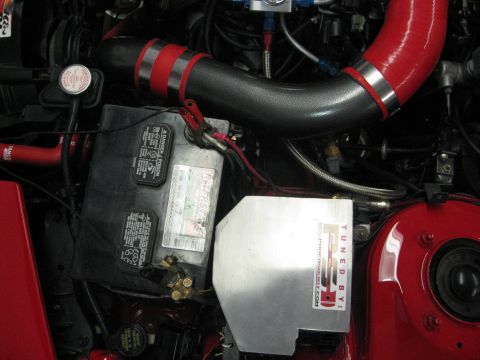 1994 Ford Probe - Close-up view of a car's engine bay, showing the battery and custom intake piping.