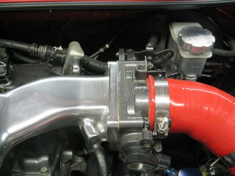 1994 Ford Probe - This image shows a close-up view of an engine's intake system, including the throttle body and a red silicone intake hose.