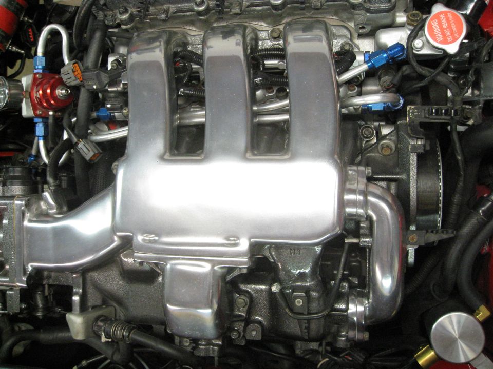 Polished aluminum intake manifold with blue fuel lines and a red fuel pressure regulator