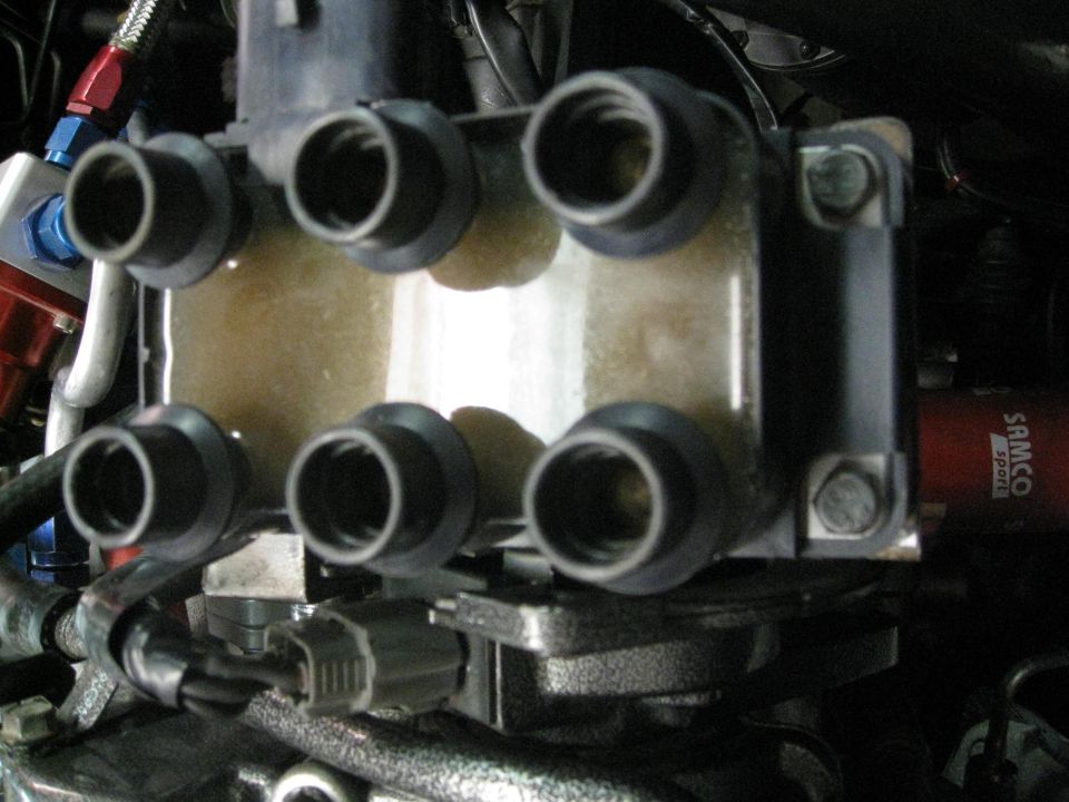 Close-up of a six-terminal ignition coil pack with yellow fluid inside