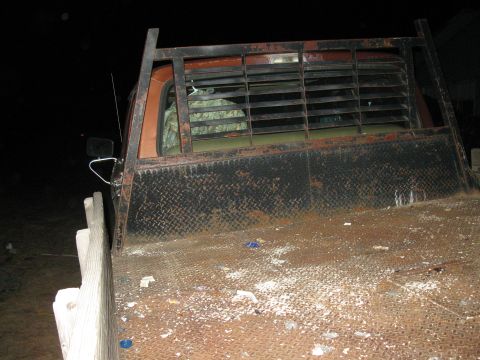 1977 Ford F-250 - Rear view of a rusty flatbed truck with a metal rack. The cab appears to be from the mid-1970s.