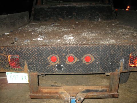 1977 Ford F-250 - The rear of a flatbed truck is shown, diamond plate metal and multiple red lights.